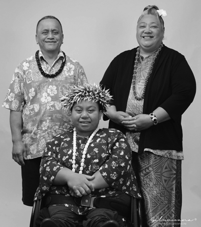 Young teenage girl on her wheelchair with her parents behind her side by side